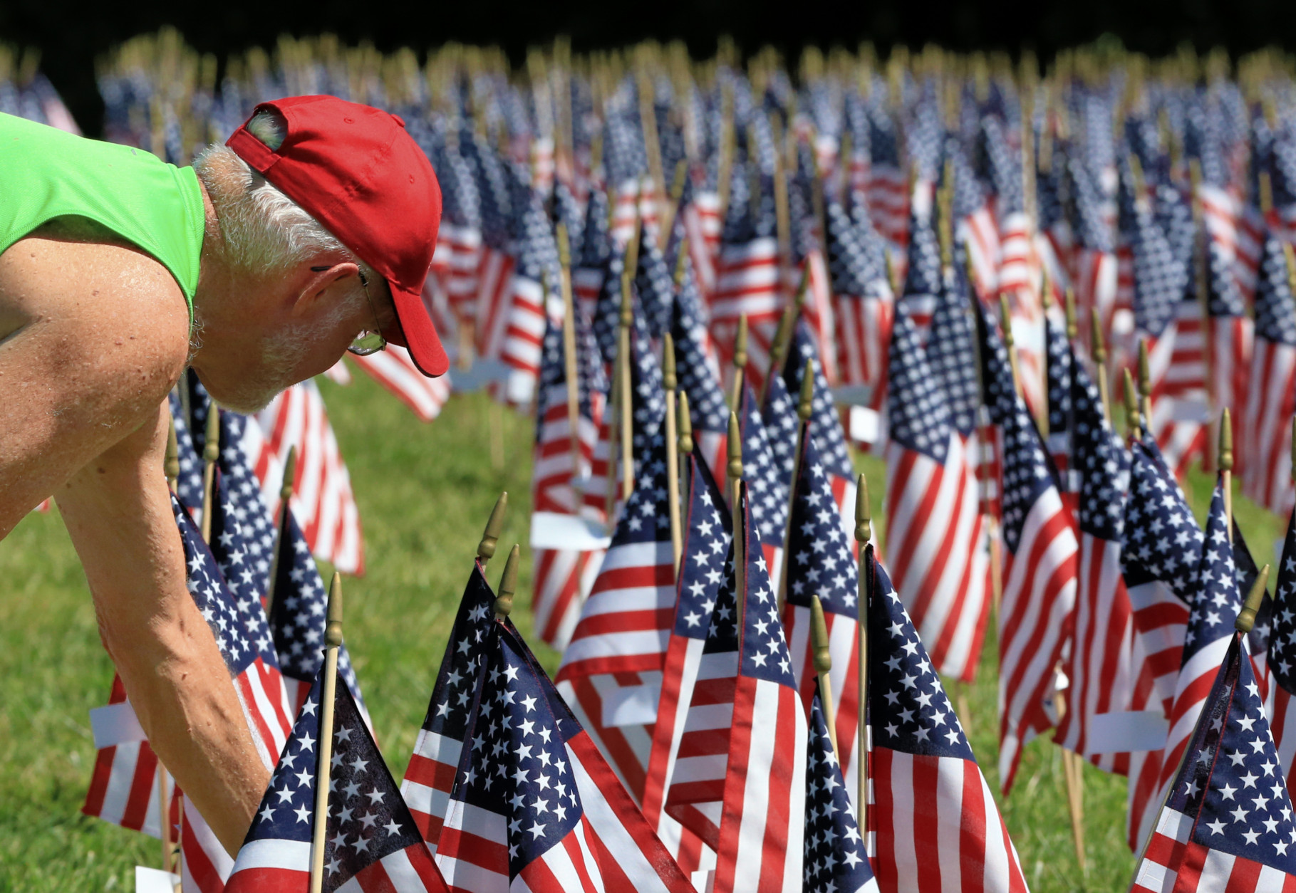 Tom Cody of Omaha searches Thursday, Sept. 10, 2015, for the flag carrying the name of a Creighton schoolmate who died in the Sept. 11 attacks in Omaha, Neb. Flags with the names of all victims were placed at Memorial Park as a tribute to the fallen. (AP Photo/Nati Harnik)