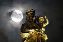 A super moon pasts behind a statue of the Virgin Mary and the Child at Notre Dame de La Garde basilica, before a total lunar eclipse, in Marseille, southern France, Monday, Sept.28, 2015. (AP Photo/Claude Paris)