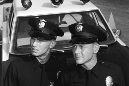 Actors Martin Milner (right) and Kent McCord stand in uniform by their patrol car in a promotional still for the television series, 'Adam 12,' c. 1969. (Photo by NBC Television/Courtesy of Getty Images)