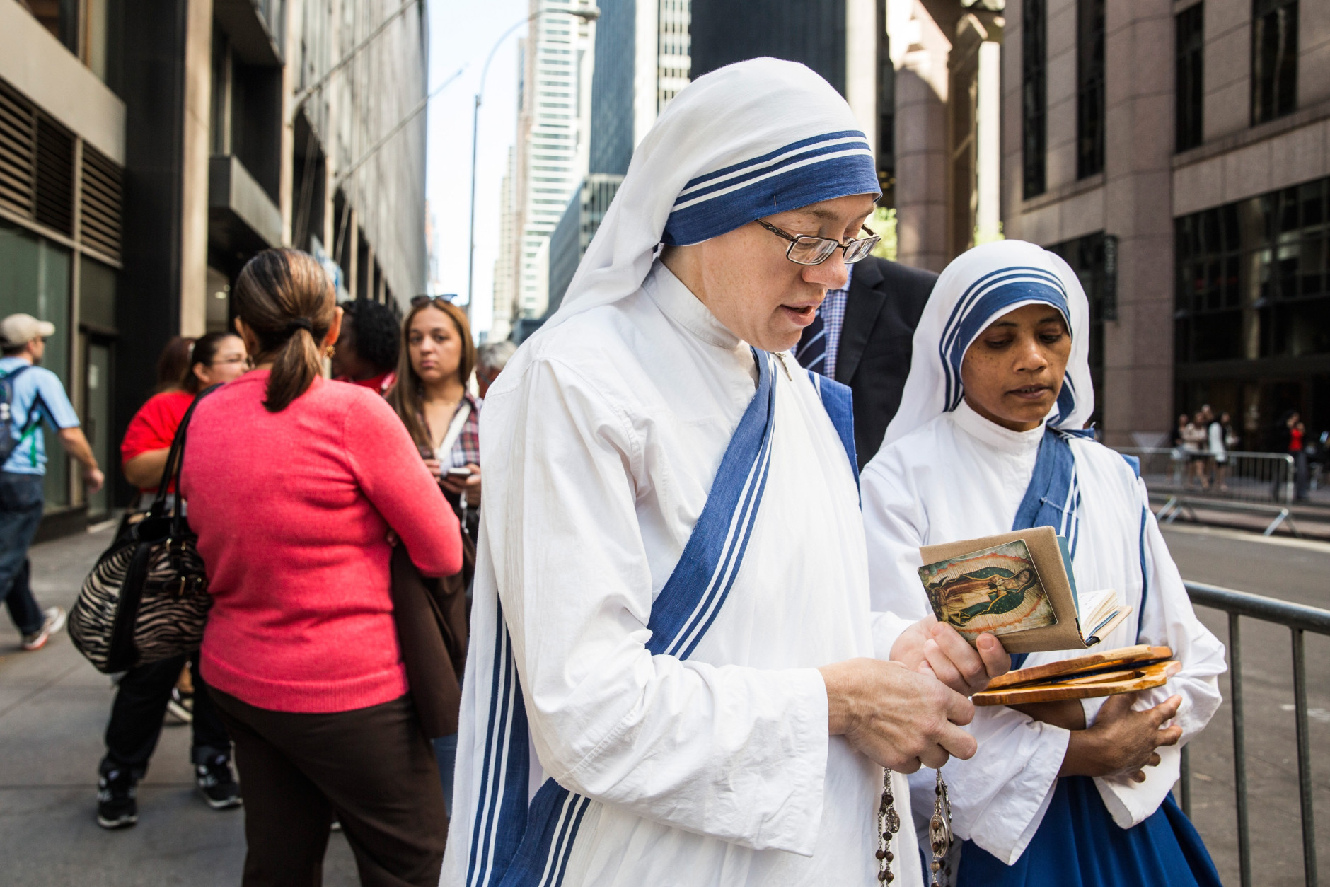 NEW YORK, NY - SEPTEMBER 24:  Sister Mary Marta (L) and Sister Marie Frank, both of Missionaries of Charity Convent, pray while waiting in line to stand along 5th Avenue to watch as Pope Francis drives by while he is en route to St. Patrick's Cathedral on September 24, 2015 in New York City.  The Pope will speak tonight at St. Patrick's Cathedral; he is scheduled to land at John F. Kennedy Airport at 5P.M. this evening.  (Photo by Andrew Burton/Getty Images)