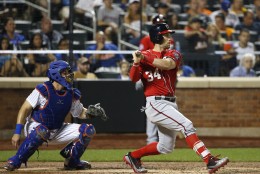 New York Mets catcher Kevin Plawecki watches as Washington Nationals Bryce Harper hits a sixth-inning single in a baseball game against the New York Mets in New York, Sunday, Aug. 2, 2015. (AP Photo/Kathy Willens)