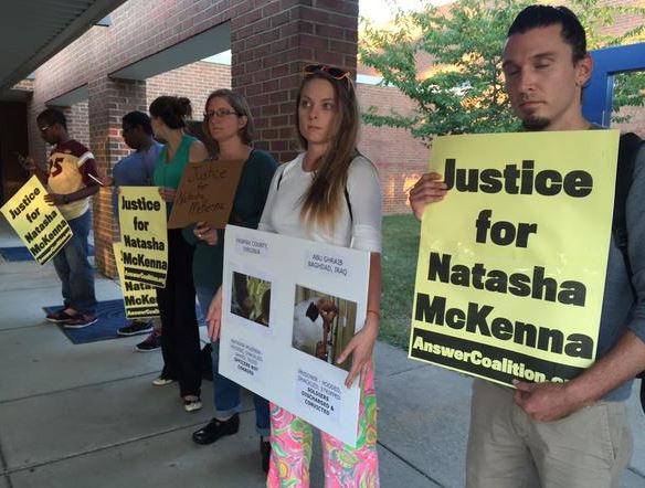 Demonstrators held signs before the Monday night public hearing. (WTOP/Michelle Basch)