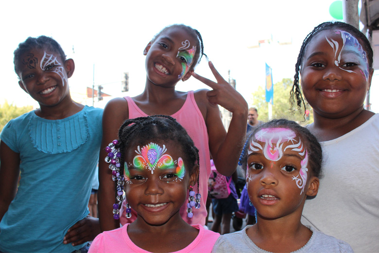 Girls show off their artwork after visiting the face painting tent. (WTOP/Dana Gooley)