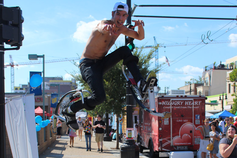 A shirtless guy on futuristic pogo stick shoes entertained crowds during the festival. (WTOP/Dana Gooley)