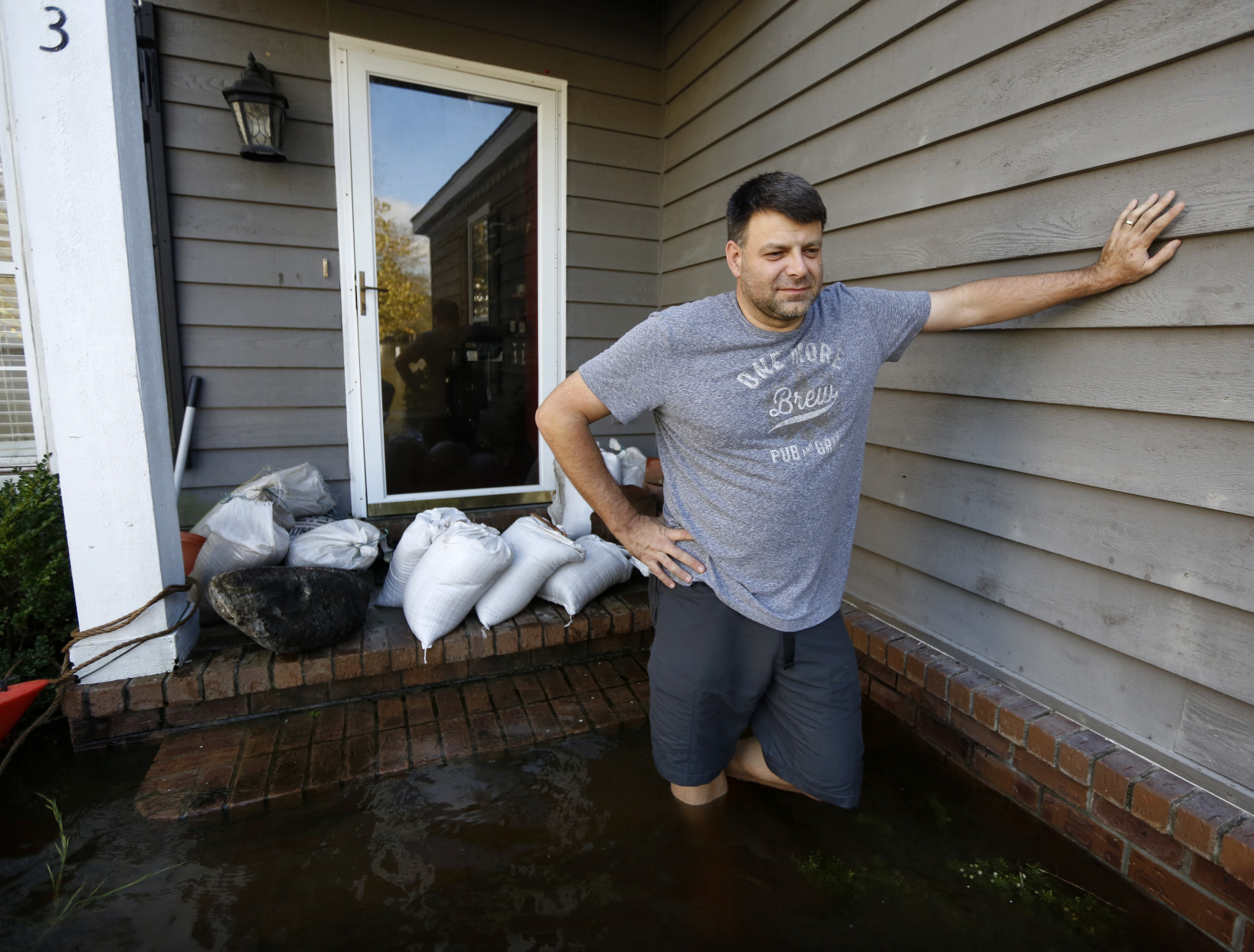 Jan-Patrick Gros looks out from his front porch of his home in the Ashborough subdivision near Summerville, S.C., Tuesday, Oct. 6, 2015. Residents are concerned that the Ashley river will continue to rise as floodwaters come down from Columbia. "I'm expecting another 2-3 feet", Gros said.  (AP Photo/Mic Smith)