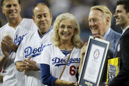 Los Angeles Dodgers broadcaster Vin Scully, second from right, is honored, with his wife Sandi Scuilly, and sons Kevin and Todd Scully, far left, before a baseball game against the Arizona Diamondbacks in Los Angeles, Wednesday, Sept. 23, 2015. Vin Scully was given a Guinness World Records certificate for the longest career as a sports broadcaster for a single team. (AP Photo/Alex Gallardo)