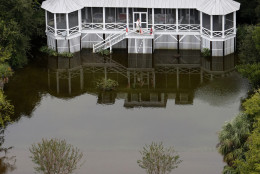 A man talks on his phone on his porch in floodwaters on Sullivan's Island, S.C., Monday, Oct. 5, 2015. The Charleston and surrounding areas are still struggling with flood waters due to a slow moving storm system. (AP Photo/Mic Smith)
