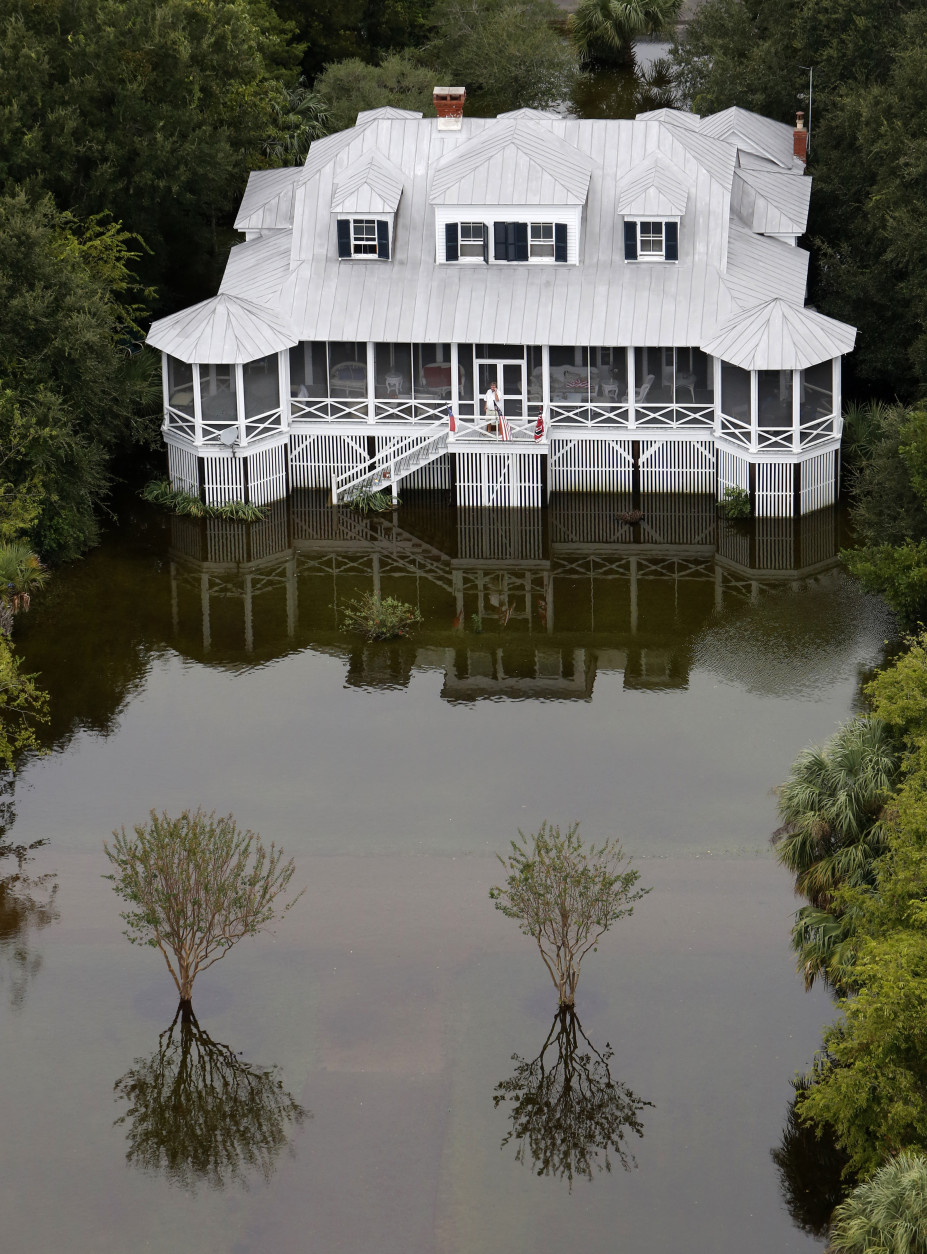 A man talks on his phone on his porch in floodwaters on Sullivan's Island, S.C., Monday, Oct. 5, 2015. The Charleston and surrounding areas are still struggling with flood waters due to a slow moving storm system. (AP Photo/Mic Smith)