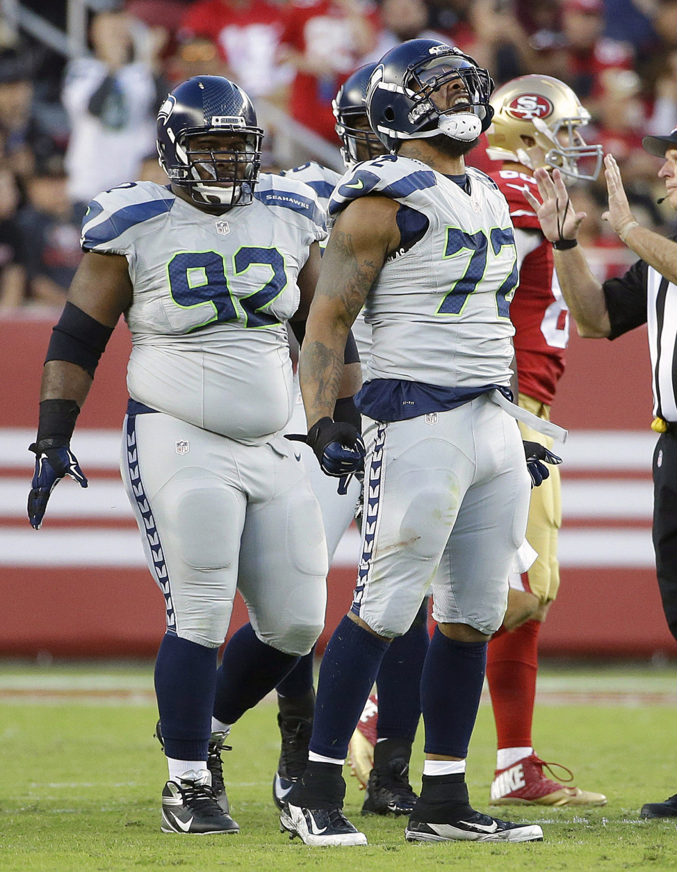 Seattle Seahawks defensive end Michael Bennett (72) reacts after sacking San Francisco 49ers quarterback Colin Kaepernick during the first half of an NFL football game in Santa Clara, Calif., Thursday, Oct. 22, 2015. Seahawks defensive tackle Brandon Mebane (92) looks on. (AP Photo/Marcio Jose Sanchez)