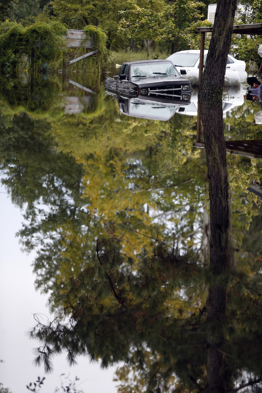 Flood waters surround cars parked behind a home in Ridgeville, S.C. (AP Photo/John Bazemore)