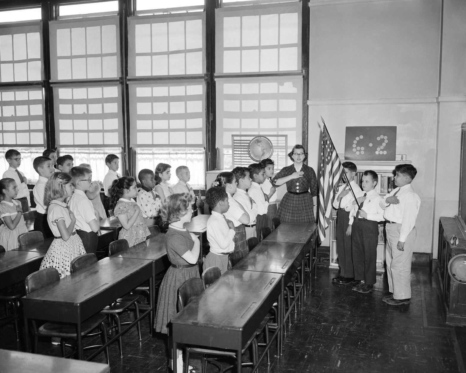 Holding the hand over the heart is the salute to the flag used in New York public schools. The old type military salute has been discontinued by a law passed in 1942.  This is a sixth grade class in P.S. 116 at 33rd street in Manhattan, Oct. 11, 1957. (AP Photo)