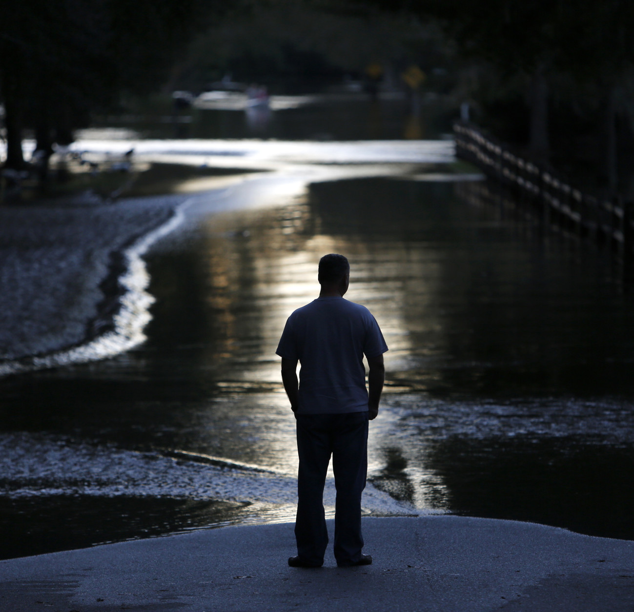 A resident looks down Mayfield St. as the Ashley river floodwaters rise in the Ashborough subdivision near Summerville, S.C., Tuesday, Oct. 6, 2015. Residents are concerned that the Ashley river will continue to rise as floodwaters come down from Columbia. (AP Photo/Mic Smith)