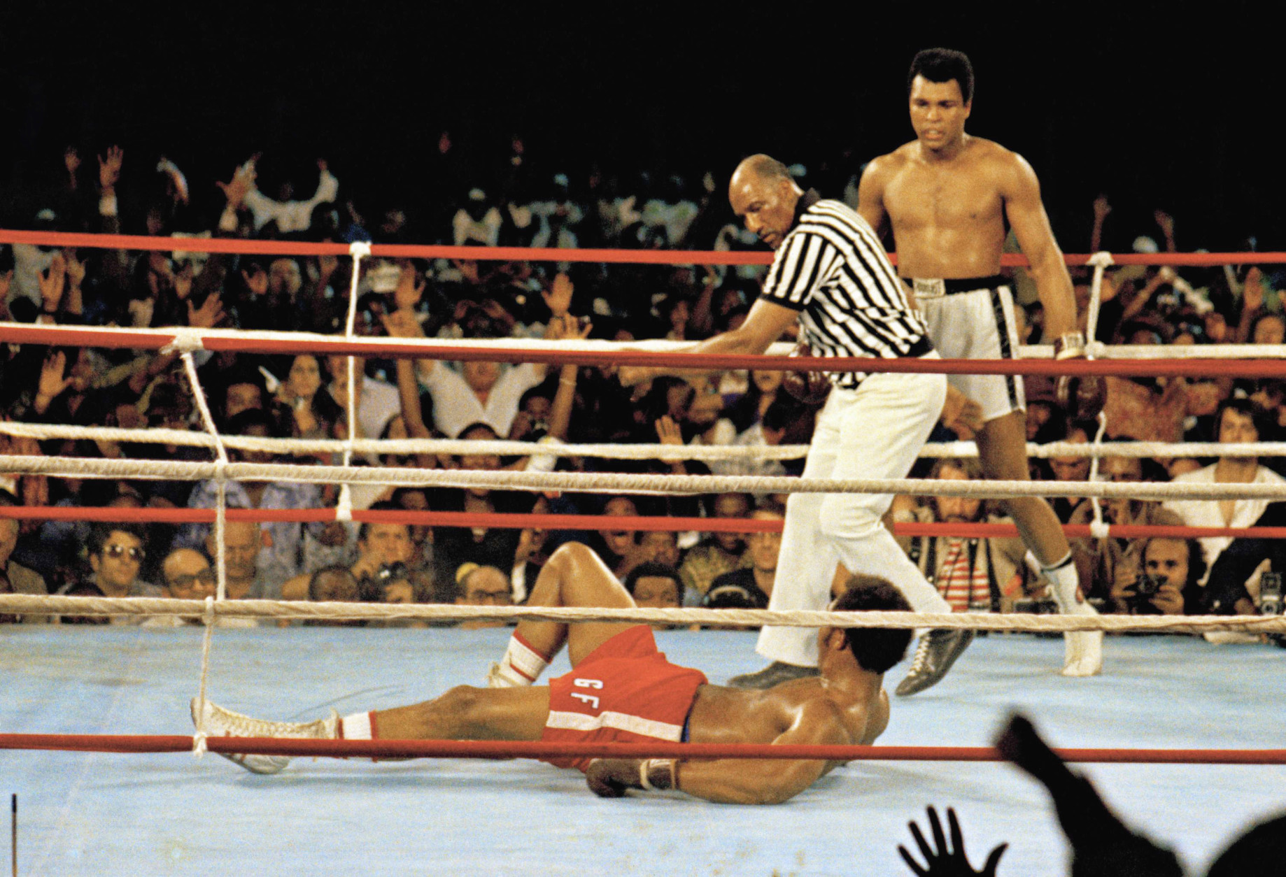 FILE - This is a  Oct. 30, 1974 file photo of Muhammad Ali, right, as he  stands back as referee Zack Clayton calls the count over opponent George Foreman, red shorts, in Kinshasa, Zaire.  Ali won the fight in Africa by a knock out in the 8th round. It was 40 years ago that two men met just before dawn on Oct. 30, 1974, to earn $5 million in the Rumble in the Jungle. In one of boxing's most memorable moments, Muhammad Ali stopped the fearsome George Foreman to recapture the heavyweight title in the impoverished African nation of Zaire. (AP Photo, File)