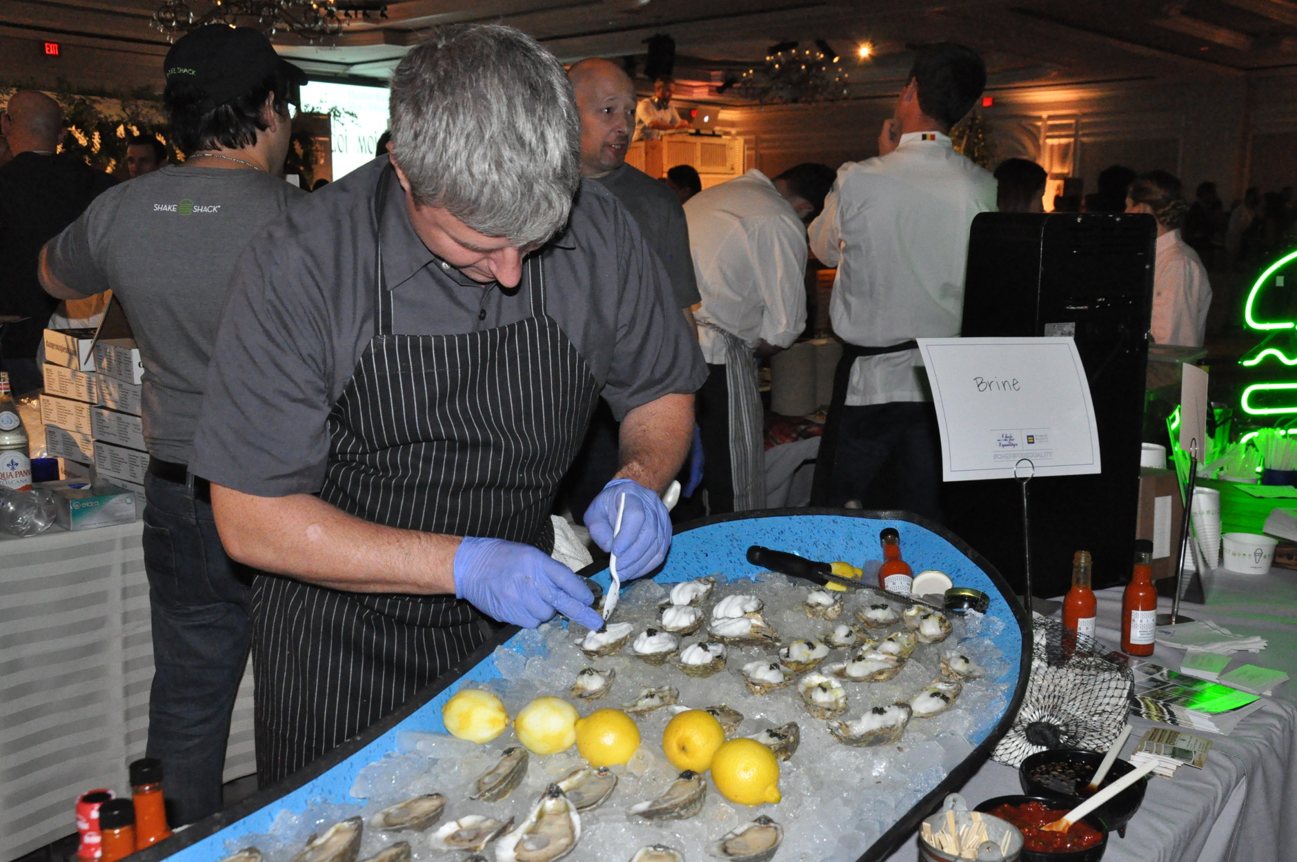 The chefs from the Mosaic District's BRINE restaurant shuck oysters for diners. (WTOP/Rachel Nania)