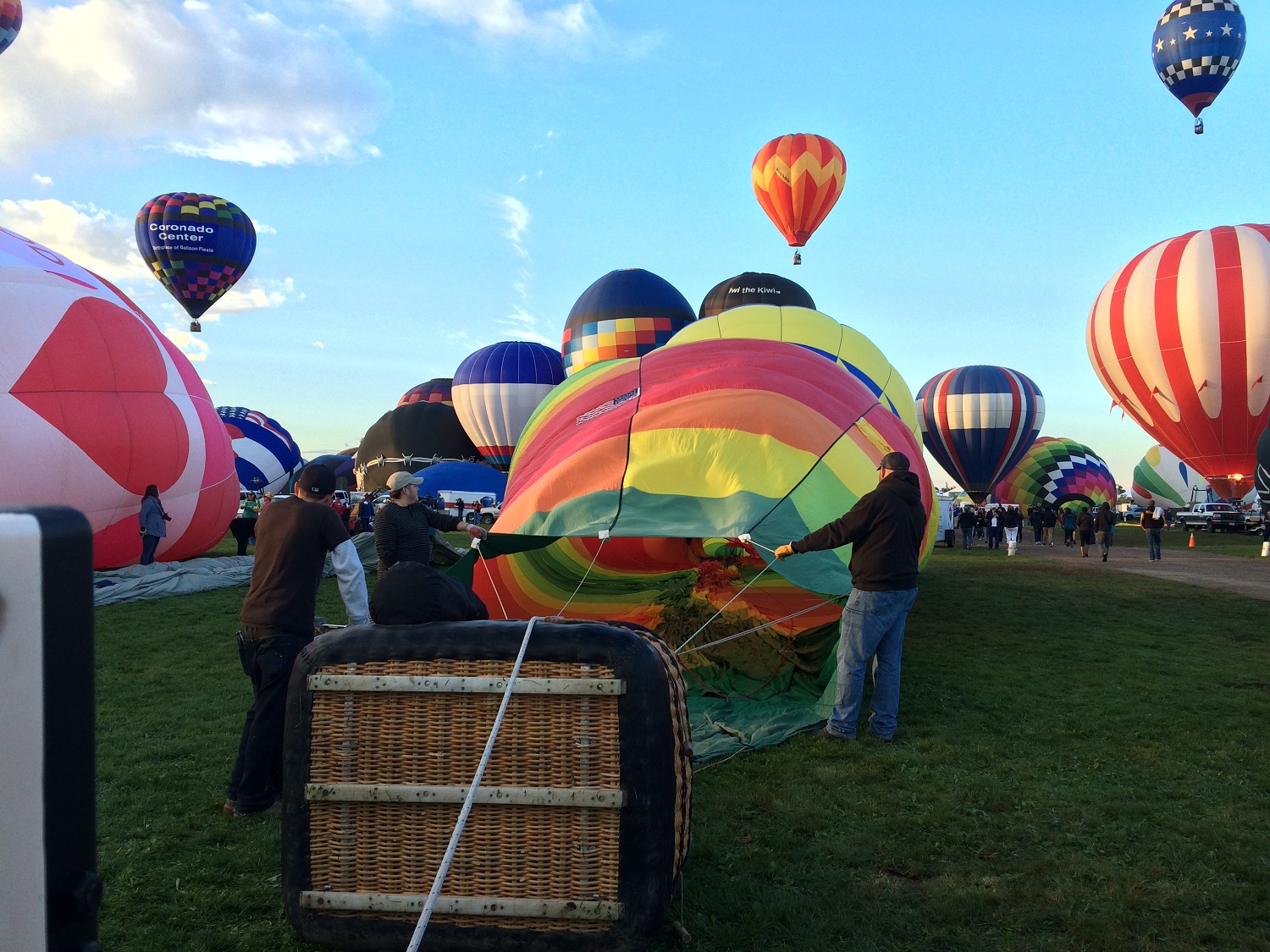 A balloon is filled in the foreground while others launch behind it. (WTOP/Noah Frank)