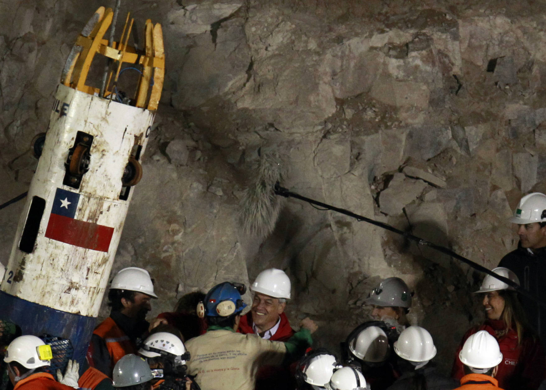 Miner Raul Bustos, center wearing blue helmet, is greeted by Chile's President Sebastian Pinera after his rescue from the collapsed San Jose gold and copper mine where he had been trapped with 32 other miners for over two months near Copiapo, Chile, Wednesday Oct. 13, 2010.   (AP Photo/Jorge Saenz)