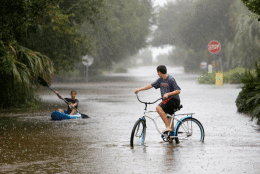 Will Cunningham, 14, rides his bike down Station 29 on Sullivan's Island, S.C., with his friend Patrick Kelly, 14, going the kayak route during flood waters on Sullivan's Island Saturday, Oct. 3, 2015. Rain pummeling parts of the East Coast showed little sign of slackening Saturday, with record-setting precipitation prolonging the soppy misery that has been eased only by news that powerful Hurricane Joaquin will not hit the U.S. (AP Photo/Mic Smith)