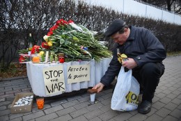 A man places a slice of bread on a plastic cup with vodka outside the French embassy in Moscow on November 14, 2015, to pay tribute to the victims of the deadly attacks in Paris. A wave of coordinated attacks left more than 120 dead in scenes of carnage in Paris Friday, including scores massacred by attackers shouting "Allahu akbar" during a rock concert and others in a suicide bombing near the national stadium. AFP PHOTO / DMITRY SEREBRYAKOV        (Photo credit should read DMITRY SEREBRYAKOV/AFP/Getty Images)