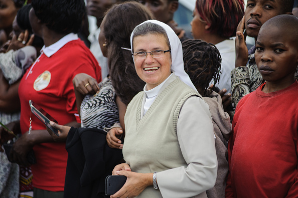 A nun waits with Kenyans to see the convoy transporting Pope Francis during his visit to Africa in Nairobi on November 25, 2015. Crowds lined Nairobi's streets to welcome the pontiff during his visit to Kenya, Uganda and the troubled Central African Republic (CAR) on a six-day trip. Vast crowds are expected to turn out to see his motorcade pass. Kenya's government has declared November 26, 2015, the first full day of his visit, in which Francis will hold a giant open air mass in central Nairobi, a public holiday and a "national day of prayer and reflection. Authorities plan to deploy over 10,000 police in the capitals of Kenya and Uganda during the pope's visit. Nairobi and Kampala are both targets for Al-Qaeda's East Africa branch, the Shebab, because they have troops deployed in Somalia. AFP PHOTO / JENNIFER HUXTA / AFP / Jennifer Huxta        (Photo credit should read JENNIFER HUXTA/AFP/Getty Images)