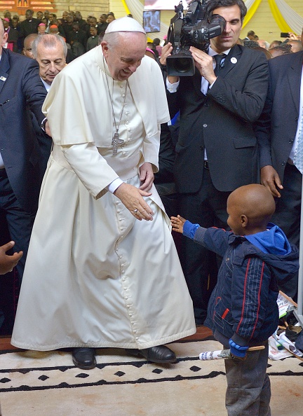 Pope Francis salutes a boy during a mass at the Church of Saint Joseph the worker in the Nairobi shanty town of Kangemi on November 27, 2015 in the Kenyan capital, Nairobi. Pope Francis lashed out at wealthy minorities who hoard resources at the expense of the poor as he visited a crowded slum in the Kenyan capital. "These are wounds inflicted by minorities who cling to power and wealth, who selfishly squander while a growing majority is forced to flee to abandoned, filthy and run-down peripheries," the 78-year-old pontiff told crowds in the Nairobi shanty town of Kangemi.  / AFP / TONY KARUMBA        (Photo credit should read TONY KARUMBA/AFP/Getty Images)