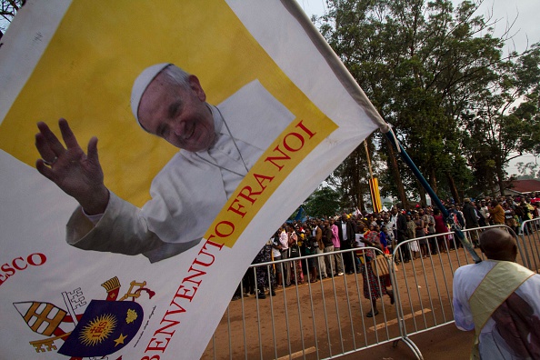 A man holds a flag with a portrait of Pope Francis as he walks to the Namugongo Catholic shrine in Namugongo on November 28, 2015, where the pontiff is slated to hold a mass. AFP PHOTO/ ISAAC KASAMANI / AFP / ISAAC KASAMANI        (Photo credit should read ISAAC KASAMANI/AFP/Getty Images)