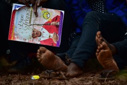A man holds a magazine with a picture of Pope Francis as people wait for the arrival of the pope for an open mass in  Kampala, Uganda, November 28, 2015. Pope Francis arrived in Uganda on November 27 on the second leg of a landmark trip to Africa which has seen him railing against corruption and poverty, with huge crowds celebrating his arrival. AFP PHOTO / GIUSEPPE CACACE / AFP / GIUSEPPE CACACE        (Photo credit should read GIUSEPPE CACACE/AFP/Getty Images)