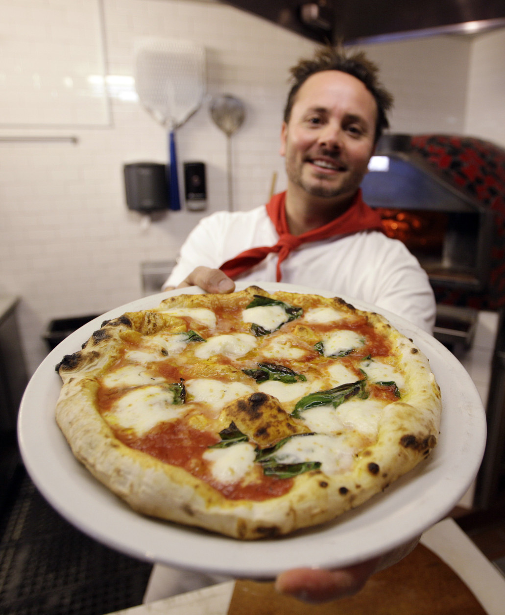 This Thursday, Jan. 27, 2011 photo shows Tony Gemignani as he holds up a pizza margherita at Tony's Pizza Napoletana in San Francisco.  Super Bowl Sunday is coming and pie-makers across the country are bracing for a pizza reaction.    (AP Photo/Eric Risberg)