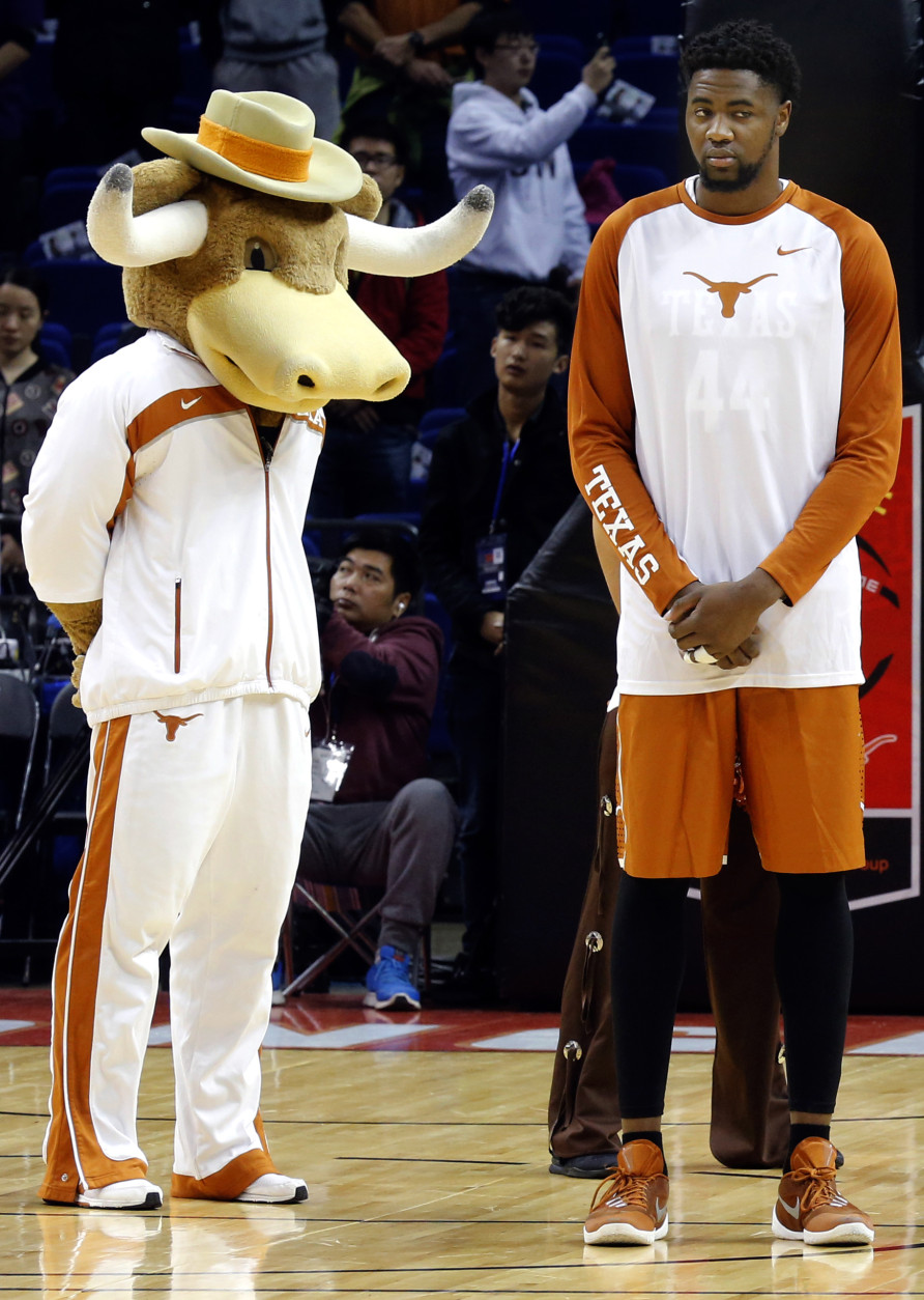 Prince Ibeh of the Texas Longhorns observes a moment of silence near the team mascot to mark the attacks in Paris before a match against the Washington Huskies at the Mercedes Benz Arena in Shanghai, China, Saturday, Nov. 14, 2015. (AP Photo/Ng Han Guan)