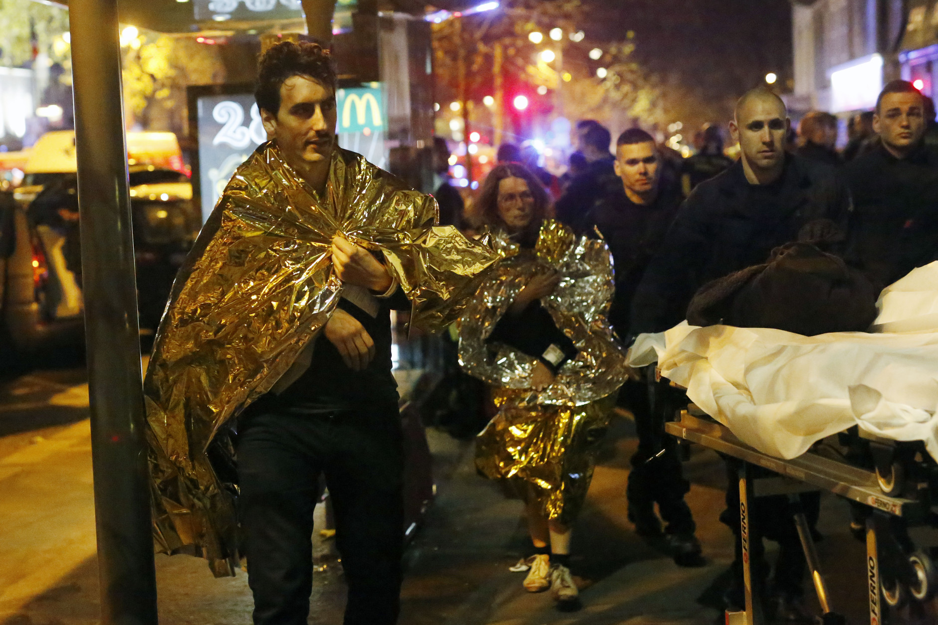 Victims walk away outside the Bataclan theater in Paris, Friday Nov. 13, 2015. Well over 100 people were killed  in a series of shooting and explosions explosions. French President Francois Hollande declared a state of emergency and announced that he was closing the country's borders. (AP Photo/Jerome Delay)