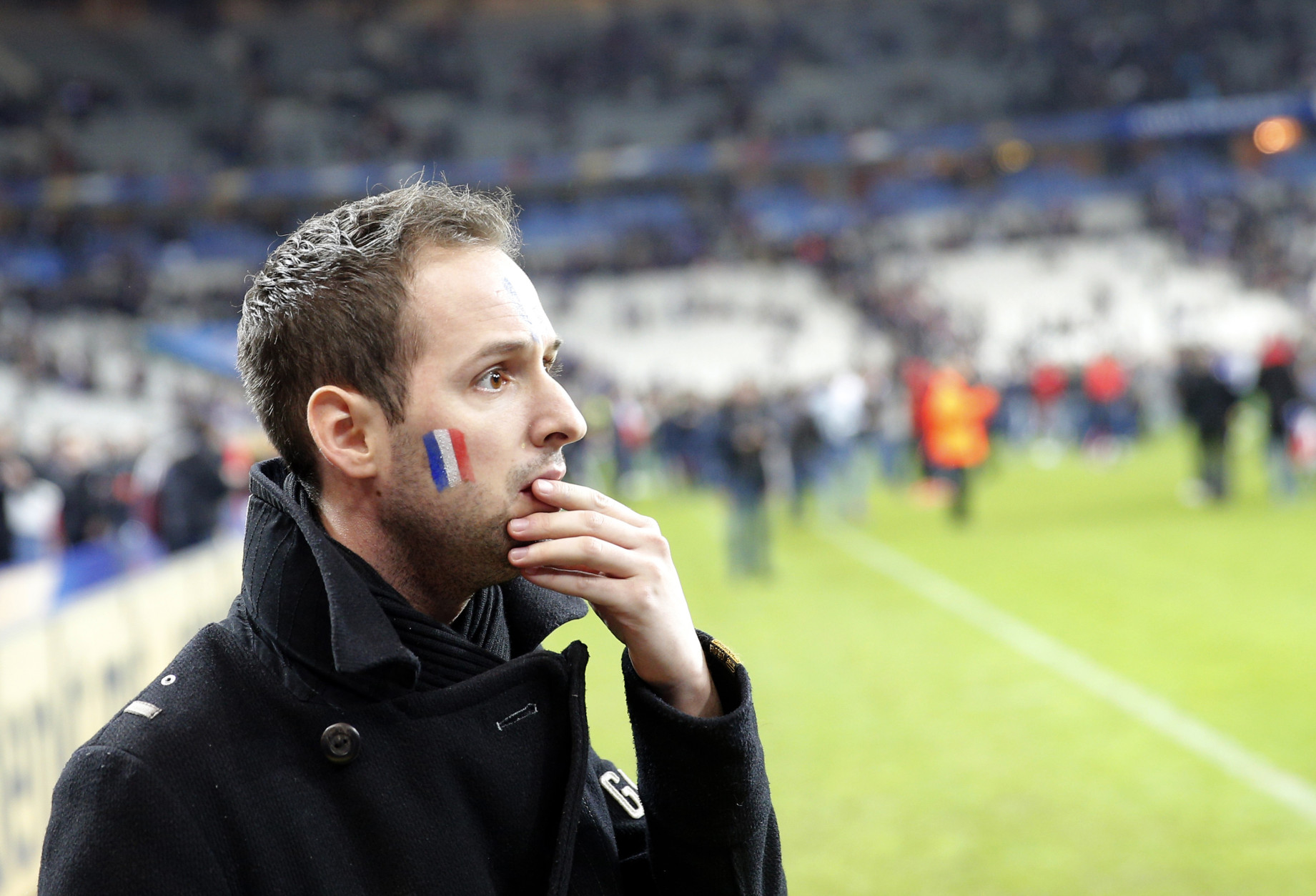 A French supporter reacts after invading the pitch of the Stade de France stadium at the end of the international friendly soccer match between France and Germany in Saint Denis, outside Paris, Friday, Nov. 13, 2015. Hundreds of people spilled onto the field of the Stade de France stadium after explosions were heard nearby. French President Francois Hollande says he is closing the country's borders and declaring a state of emergency after several dozen people were killed in a series of unprecedented terrorist attacks. (AP Photo/Christophe Ena)
