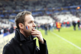 A French supporter reacts after invading the pitch of the Stade de France stadium at the end of the international friendly soccer match between France and Germany in Saint Denis, outside Paris, Friday, Nov. 13, 2015. Hundreds of people spilled onto the field of the Stade de France stadium after explosions were heard nearby. French President Francois Hollande says he is closing the country's borders and declaring a state of emergency after several dozen people were killed in a series of unprecedented terrorist attacks. (AP Photo/Christophe Ena)
