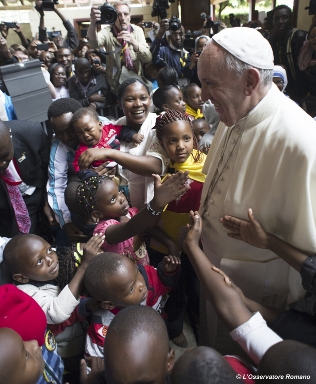 Pope Francis is cheered by children during his visit to Kangemi, one of the 11 slums dotting Nairobi, Kenya, Friday, Nov. 27, 2015. Pope Francis denounced the conditions slum-dwellers are forced to live in, saying Friday that access to safe water is a basic human right and that everyone should have dignified, adequate housing. (L'Osservatore Romano/Pool Photo via AP)
