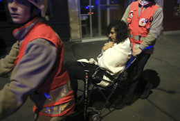 A woman is being evacuated from the Bataclan theater after a shooting in Paris, Friday Nov. 13, 2015.  French President Francois Hollande declared a state of emergency and announced that he was closing the country's borders. (AP Photo/Thibault Camus)