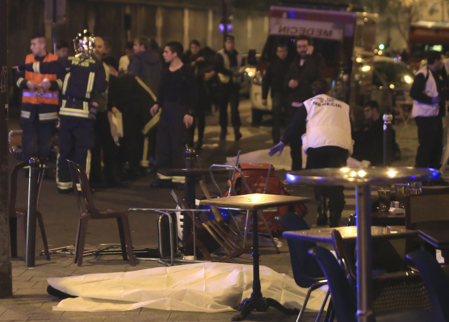 RETRANSMISSION FOR ALTERNATIVE CROP - Emergency services attewnd the scene as victims lay on the pavement outside a Paris restaurant, Friday, Nov. 13, 2015.  Police officials in France on Friday report multiple terror incidents, leaving many dead.  It was unclear at this stage if the events are linked. (AP Photo/Thibault Camus)
