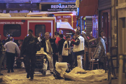 Police officers and rescue workers gather around a victim outside in the 10th district of Paris, Friday, Nov. 13, 2015.  At least 35 people were killed Friday in shootings and explosions around Paris, many of them in a popular concert hall where patrons were taken hostage, police and medical officials said. (AP Photo/Jacques Brinon)