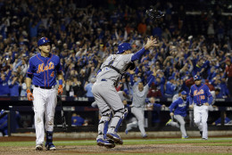 New York Mets' Wilmer Flores walks off the field after striking out as Kansas City Royals catcher Drew Butera celebrates after Game 5 of the Major League Baseball World Series Monday, Nov. 2, 2015, in New York. The Royals won 7-2 to win the series. (AP Photo/David J. Phillip)