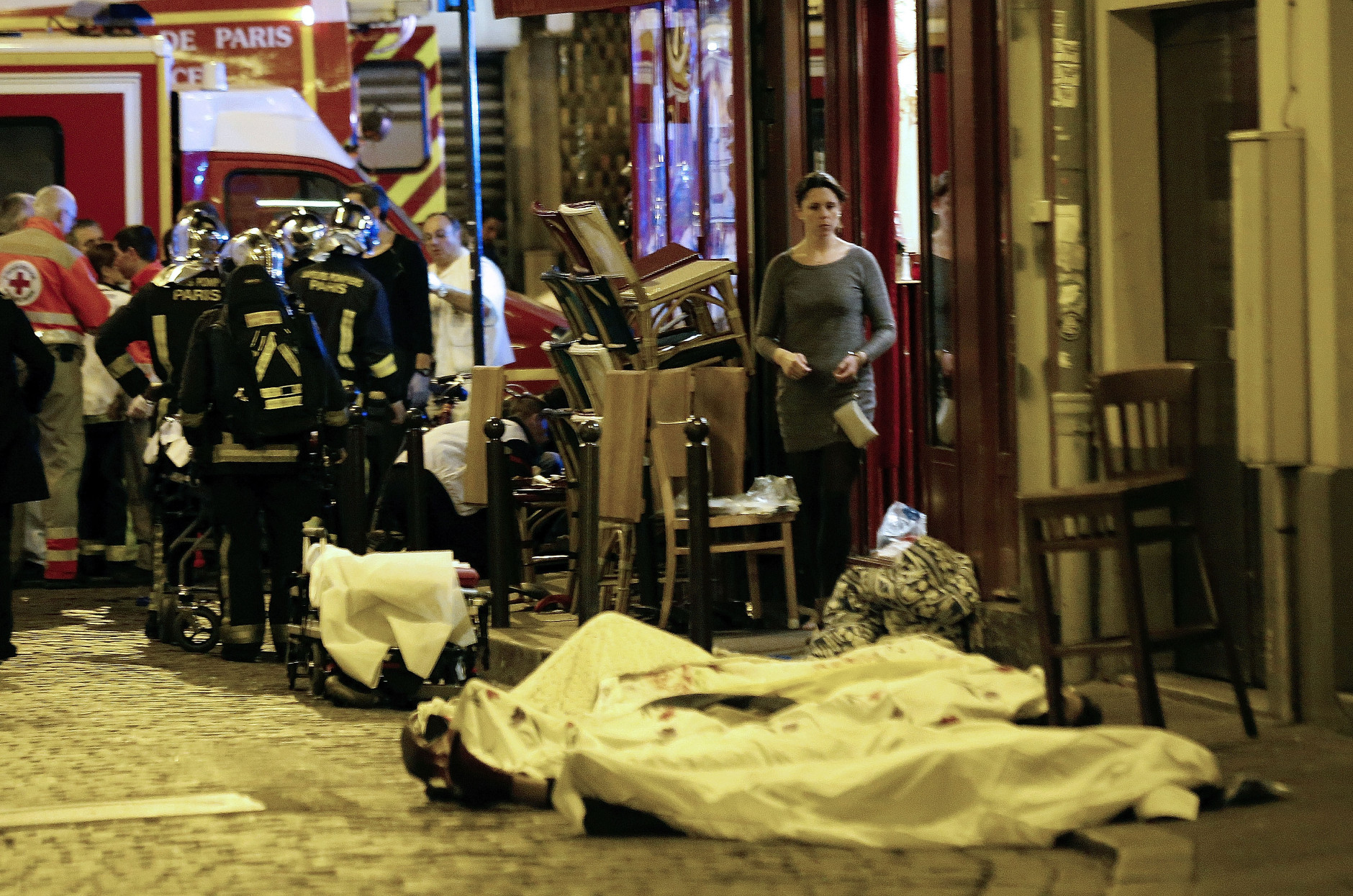A woman watches victims in the 10th district of Paris, Friday, Nov. 13, 2015.  At least 35 people were killed Friday in shootings and explosions around Paris, many of them in a popular concert hall where patrons were taken hostage, police and medical officials said. (AP Photo/Jacques Brinon)