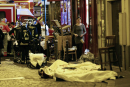 A woman watches victims in the 10th district of Paris, Friday, Nov. 13, 2015.  At least 35 people were killed Friday in shootings and explosions around Paris, many of them in a popular concert hall where patrons were taken hostage, police and medical officials said. (AP Photo/Jacques Brinon)