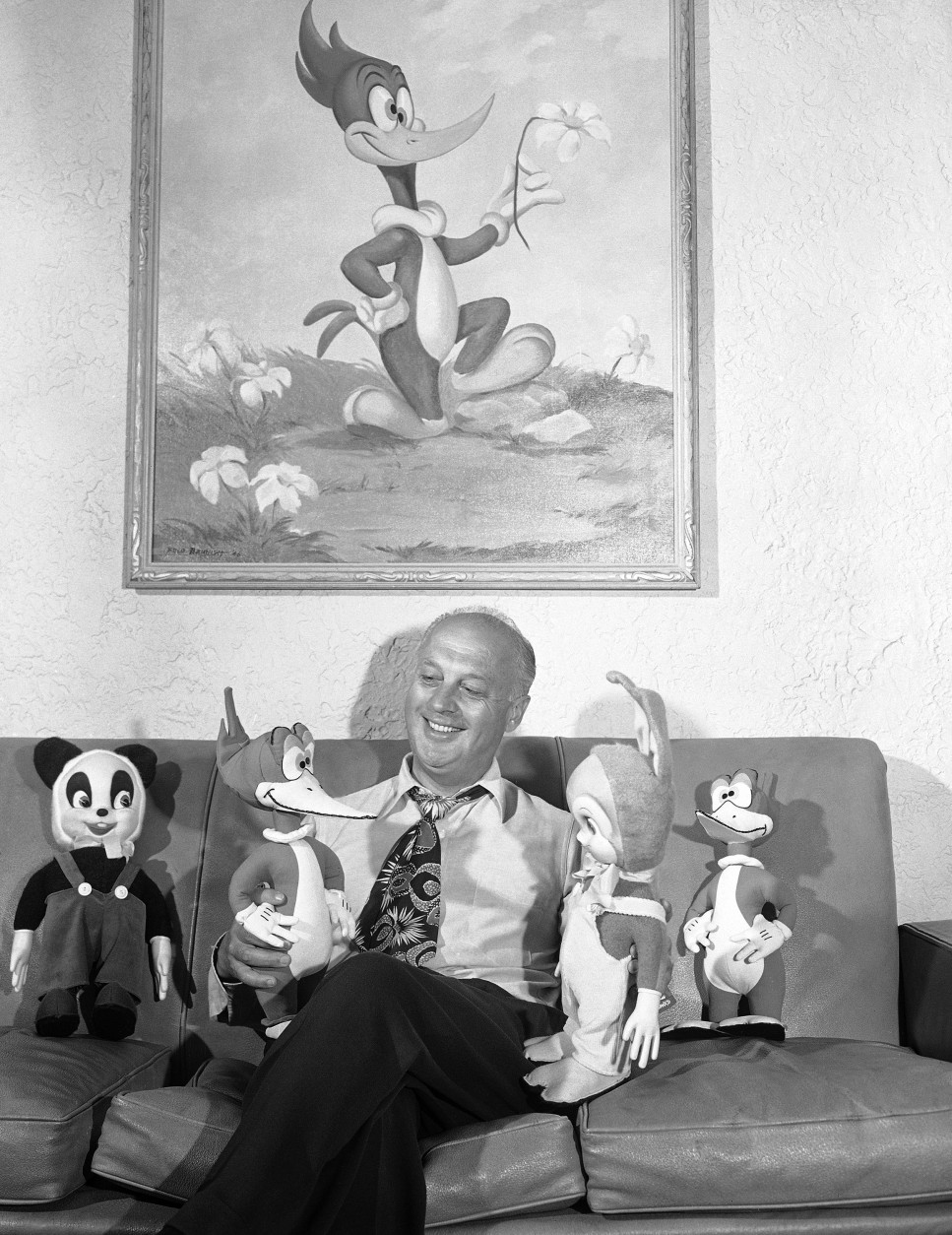 Animated cartoon motion picture producer Walter Lantz sits with dolls inspired by some of his cartoon stars in his office in Hollywood, Los Angeles on August 20, 1948. He holds Woody Woodpecker and Oswald Rabbit. Alongside of him are Andy Panda and another Woody Woodpecker. The last named is also shown in the painting hanging on the wall. Lantz, a graduate of the Art Students League in New York City, began in the animated cartoon field in 1916. (AP Photo/Don Brinn)