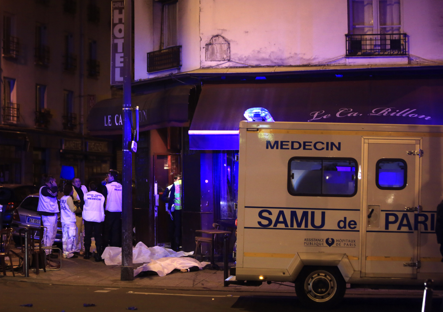 Medical staff stand by victims in a Paris restaurant, Friday, Nov. 13, 2015. Two police officials say at least 11 people have been killed in shootouts and other violence around Paris. Police have reported shootouts in at least two restaurants in Paris. At least two explosions have been heard near the Stade de France stadium, and French media is reporting of a hostage-taking in the capital. (AP Photo/Thibault Camus)