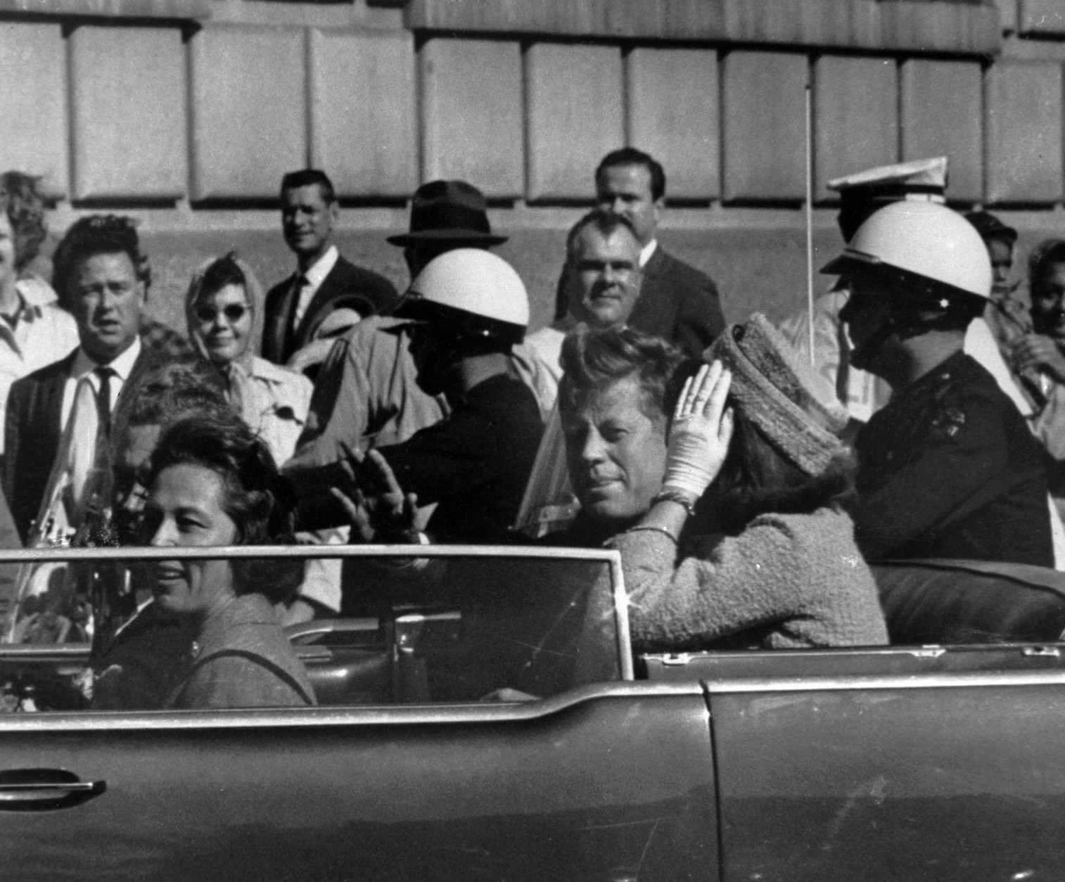 President John F. Kennedy is seen riding in motorcade approximately one minute before he was shot in Dallas, Tx., on Nov. 22, 1963.  In the car riding with Kennedy are Mrs. Jacqueline Kennedy, right, Nellie Connally, left, and her husband, Gov. John Connally of Texas.  (AP Photo/Jim Altgens)