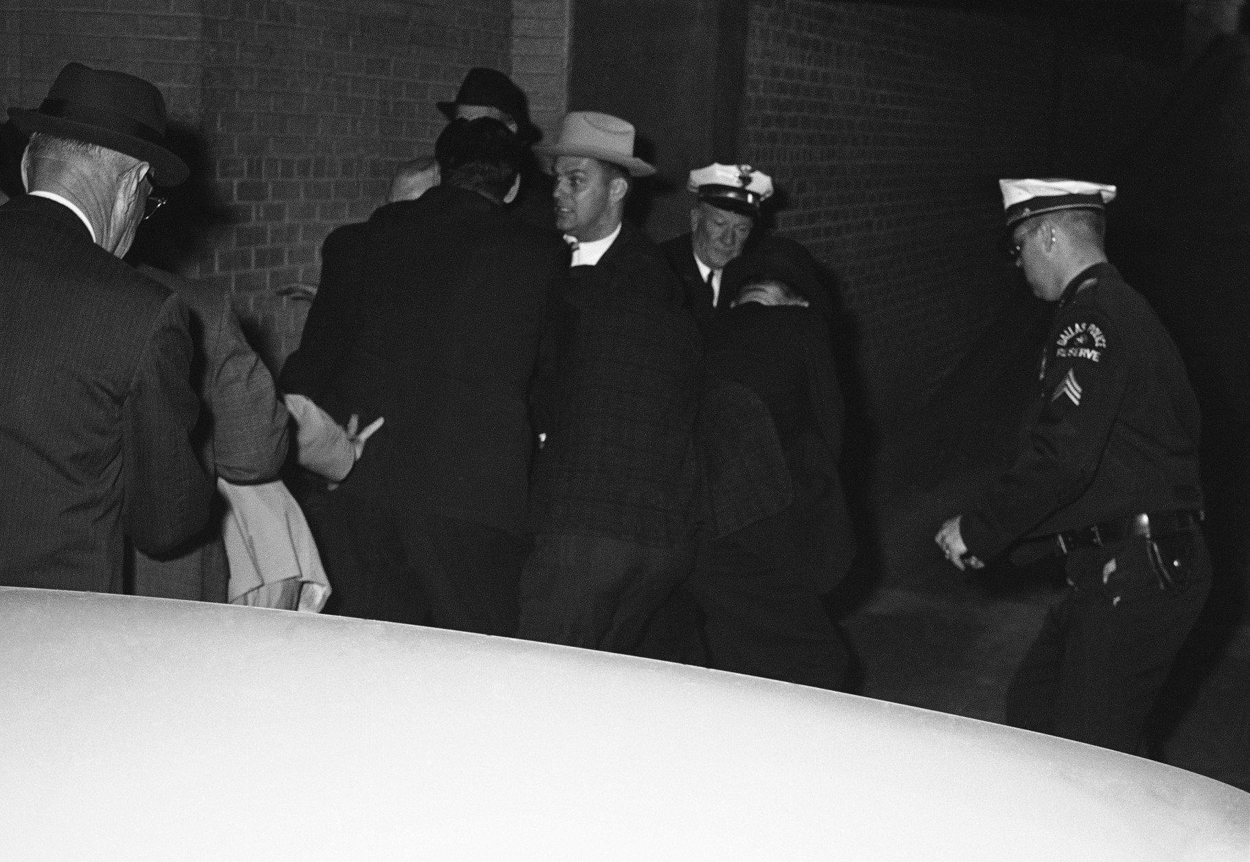 Plainclothes officers of the Dallas Police Department struggle with a man, identified as nightclub owner Jack Ruby, moments after he shot Lee Harvey Oswald, accused assassin of President Kennedy, outside the Dallas City Jail, Nov. 24, 1963 in Dallas. Ruby is not visible. (AP Photo/David F. Smith)