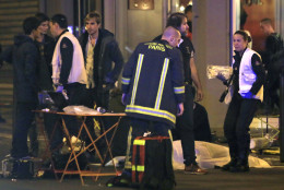 RETRANSMISSION FOR ALTERNATIVE CROP - Rescue workers at the scene as victims lay on the pavement outside a Paris restaurant, Friday, Nov. 13, 2015.  Police officials in France on Friday report multiple terror incidents, leaving many dead.  It was unclear at this stage if the events are linked. (AP Photo/Thibault Camus)