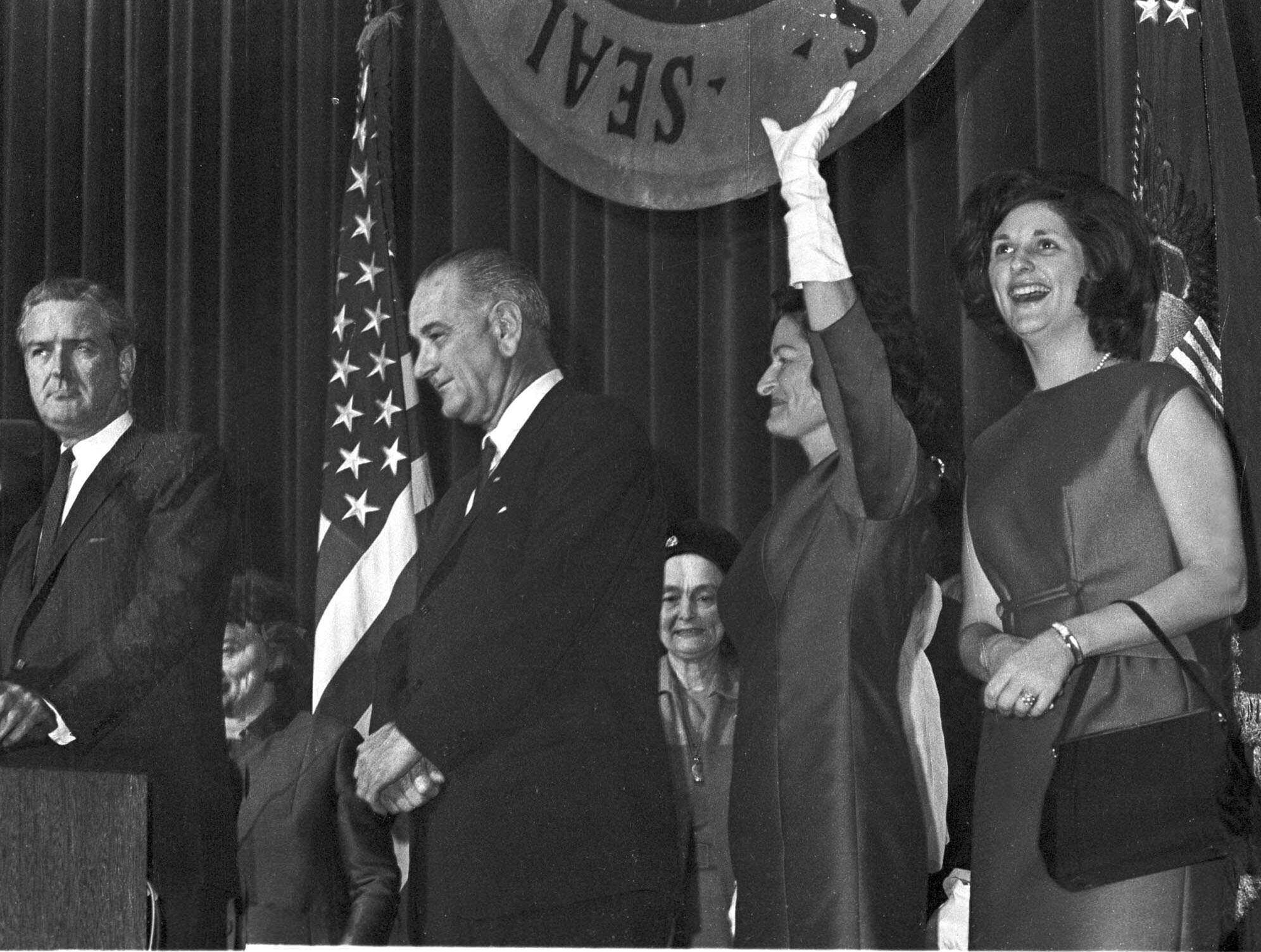** FILE ** In this Nov. 4, 1964, file photo, President Lyndon B. Johnson stands with hands folded Nov. 4, 1964 as his wife, Lady Bird Johnson and daughter Lynda Bird, right, acknowledge cheers of crowds that jammed Austin Memorial Auditorium to honor the President on his victory.  Johnson, who carried the nickname "Landslide Lyndon" for his razor-thin 87-vote victory in a Texas Senate race, won over Barry Goldwater in 1964, 486-52. Texas Gov. John Connally is left, at podium. (AP Photo/File)