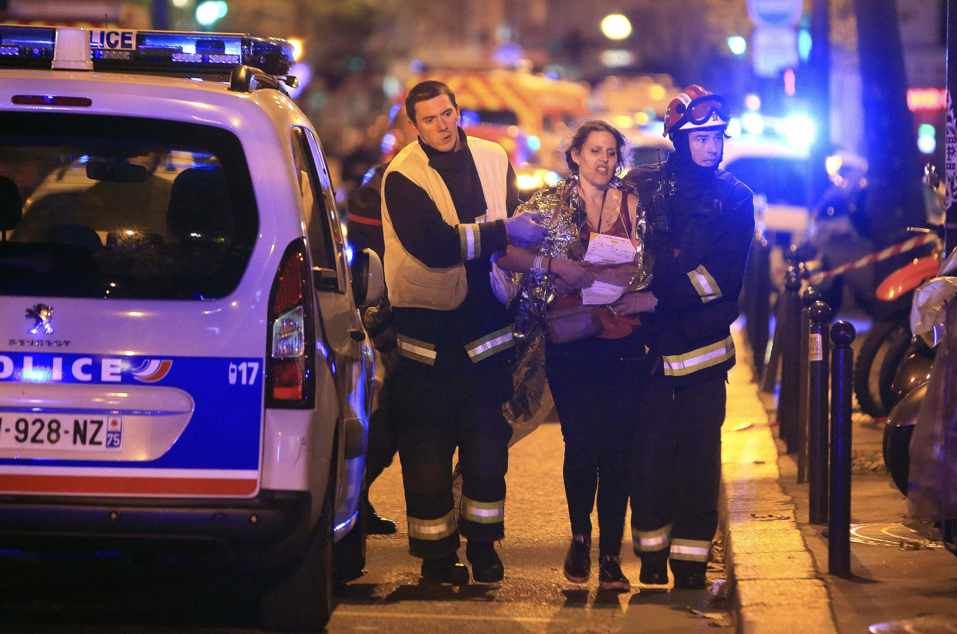 Rescue workers help a woman after a shooting, outside the Bataclan theater in Paris, Friday Nov. 13, 2015.  French President Francois Hollande declared a state of emergency and announced that he was closing the country's borders. (AP Photo/Thibault Camus)