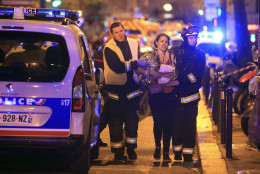 Rescue workers help a woman after a shooting, outside the Bataclan theater in Paris, Friday Nov. 13, 2015.  French President Francois Hollande declared a state of emergency and announced that he was closing the country's borders. (AP Photo/Thibault Camus)