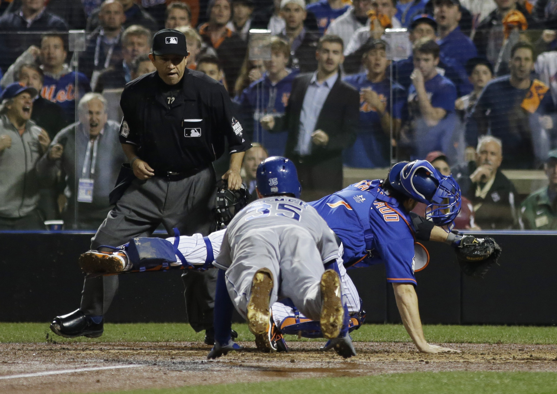 Home plate umpire Alfonso Marquez watches as Kansas City Royals' Eric Hosmer dives to score past New York Mets catcher Travis d'Arnaud during the ninth inning of Game 5 of the Major League Baseball World Series Sunday, Nov. 1, 2015, in New York. (AP Photo/Matt Slocum)