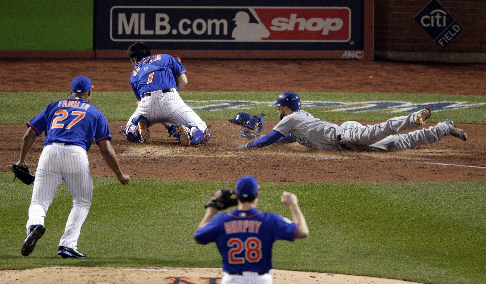 Kansas City Royals' Eric Hosmer right, scores past New York Mets catcher Travis d'Arnaud as relief pitcher Jeurys Familia (27) and second baseman Daniel Murphy (28) look on during the ninth inning of Game 5 of the Major League Baseball World Series Sunday, Nov. 1, 2015, in New York. (AP Photo/Charlie Riedel)