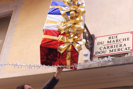 Jean Pierre Lellouche hangs a decoration in the colors of France, above his shop in Nice, southeastern France, Friday, Nov. 27, 2015. French President Francois Hollande called on his compatriots to hang French tricolor flags on Friday to pay homage to the  victims of the Nov. 13, attacks, an unusual appeal by a Socialist leader in a country where flag-waving is often associated with nationalists and the far right. (AP Photo/Lionel Cironneau)