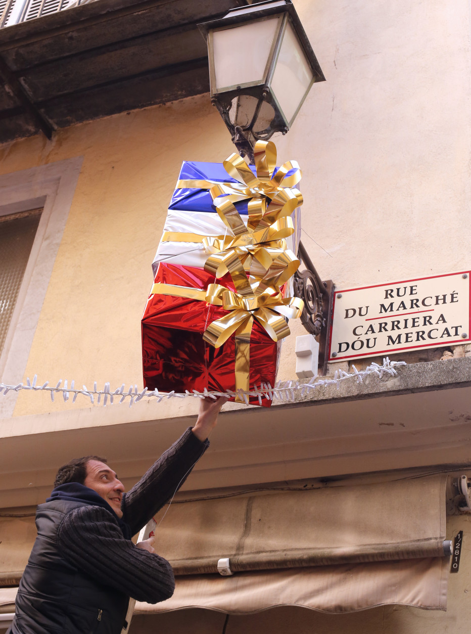 Jean Pierre Lellouche hangs a decoration in the colors of France, above his shop in Nice, southeastern France, Friday, Nov. 27, 2015. French President Francois Hollande called on his compatriots to hang French tricolor flags on Friday to pay homage to the  victims of the Nov. 13, attacks, an unusual appeal by a Socialist leader in a country where flag-waving is often associated with nationalists and the far right. (AP Photo/Lionel Cironneau)